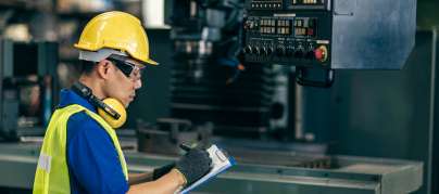Trabajador con casco inspecciona planta de producción en fábrica asiática