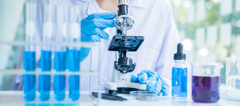 Laboruntersuchung mit Mikroskop und blauen Proben im Reagenzglas